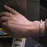 Hand with AMANDA PEARL recycled sterling silver rings and cuff with a metro card going into the nyc subway.