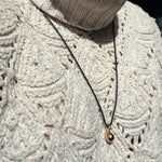 Molten Drop Charm on Quill Cording over a cream sweater.