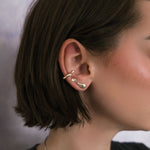 Close-up of a model wearing AMANDA PEARL recycled sterling silver earrings and ear cuff with a blurred background