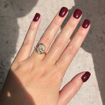 14k yellow gold molten knot ring with diamond on a model's hand with deep red nail polish.