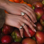 Close-up of hands with AMANDA PEARL sterling silver rings on a pile of red apples.