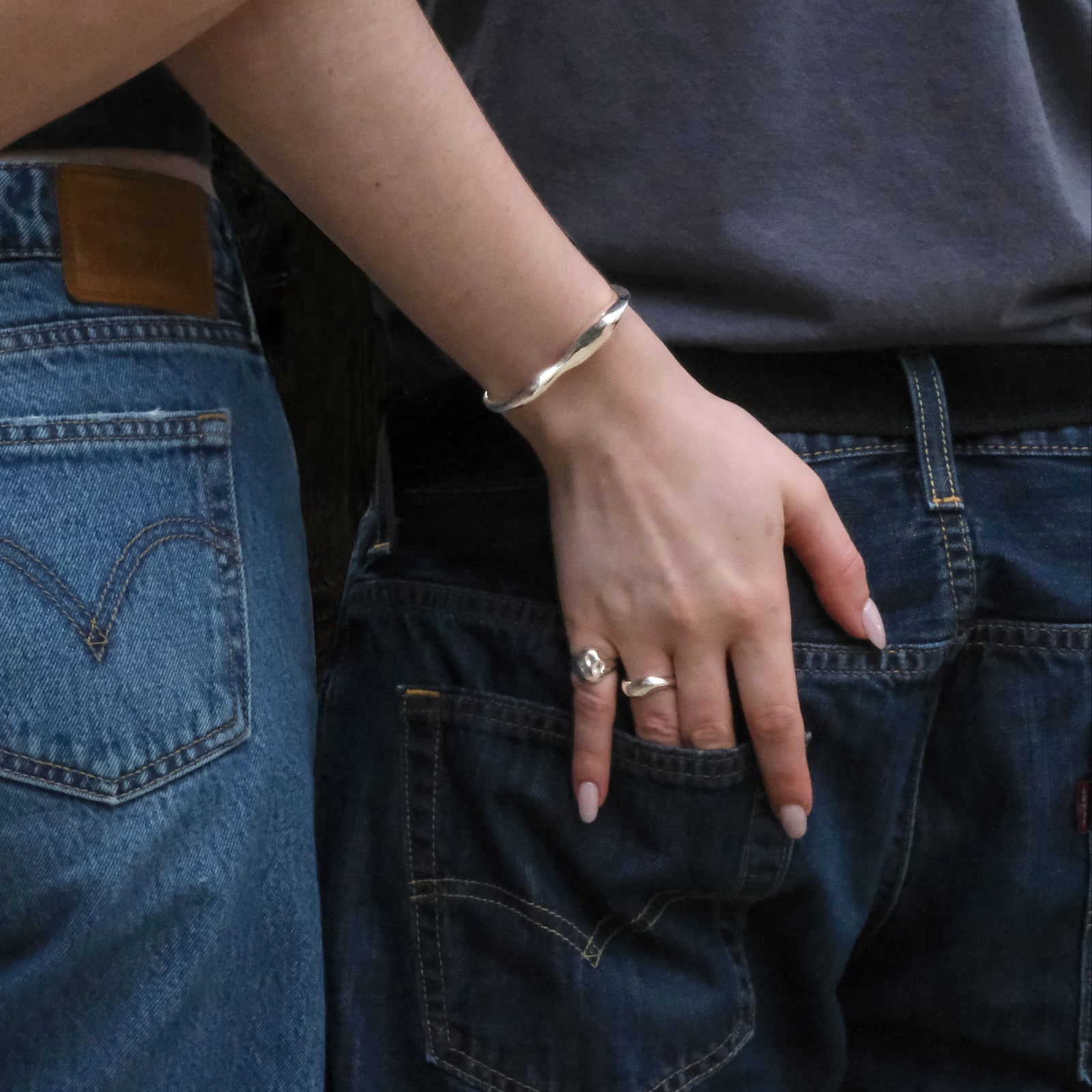 Model's hand wearing AMANDA PEARL Molten Sterling Silver jewelry with her hand in her boyfriend's back pocket.