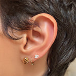 AMANDA PEARL recycled 14k gold molten skull stud with ripple huggie and marquise elements stud on a model's ear.