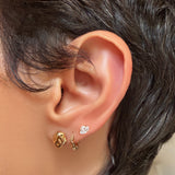 AMANDA PEARL recycled 14k gold molten skull stud with ripple huggie and marquise elements stud on a model's ear.
