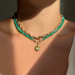 Yellow gold chain with green opal beaded necklace and round charm set with a light green peridot stone layered on neck.