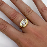 An AMANDA PEARL recycled 14k yellow gold molten solitaire ring with oval cut ethical diamond on a model's hand.
