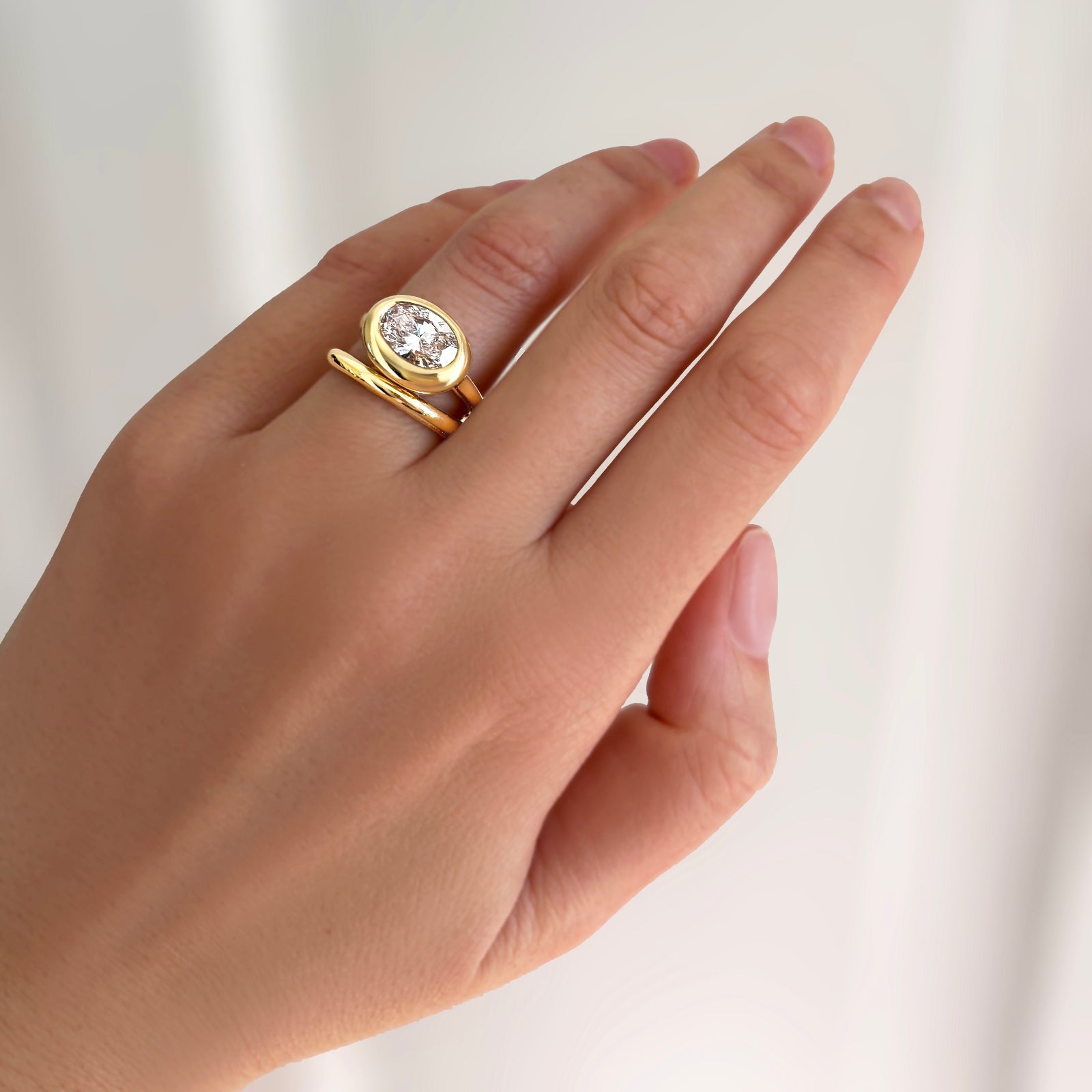 Molten solitaire ring with oval diamond with molten band on a model's hand.