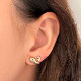An AMANDA PEARL recycled 14k gold small molten stud nestled next to a molten stud with ethical diamond pavé on a model's ear.