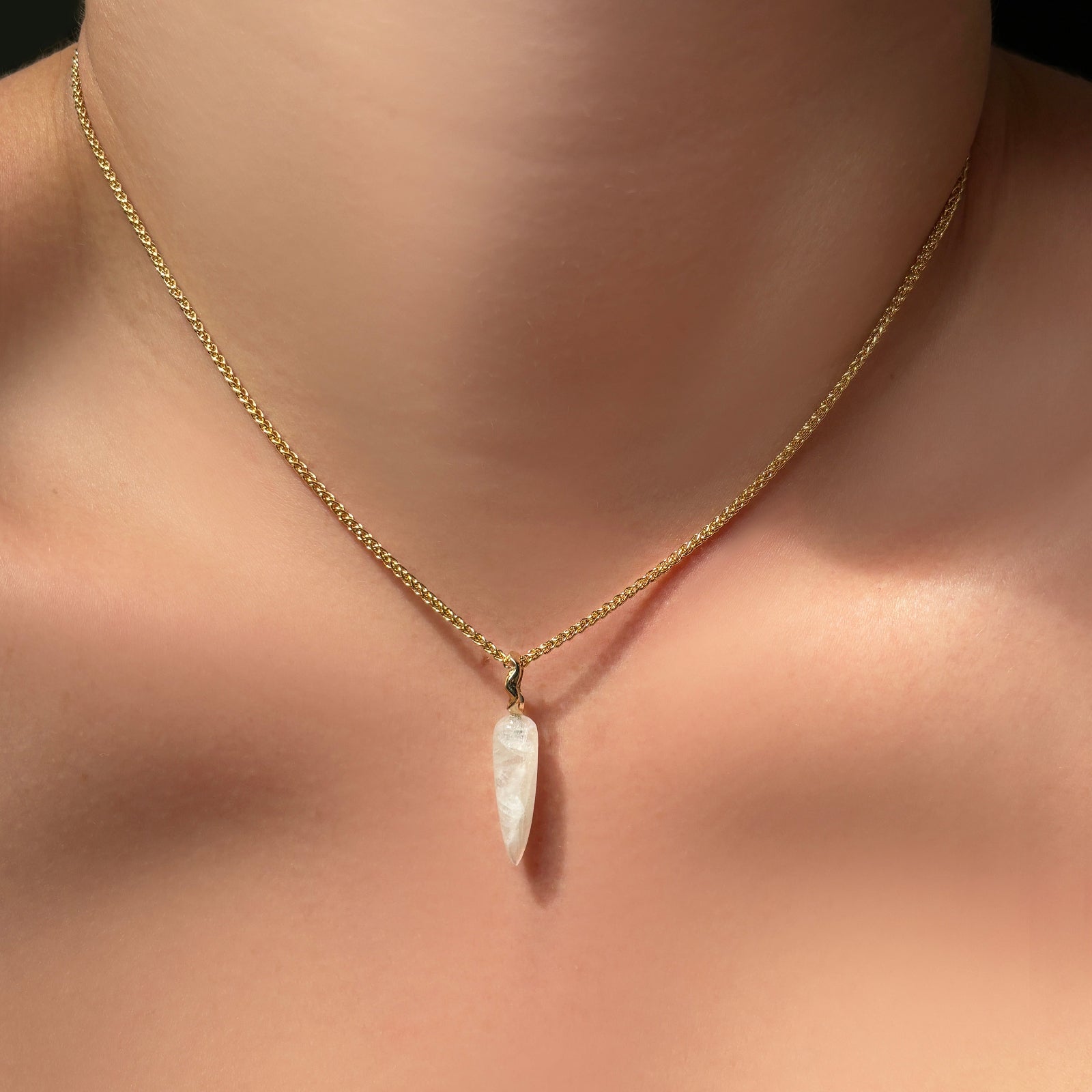 Moonstone drop charm on a wheat chain on the body.