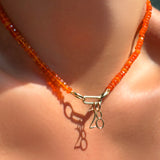 number charms on an orange faceted opal necklace dropped from a small paperclip charm lock on the neck.