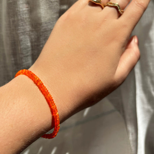 Shimmering beaded bracelet made of smooth opals in shades of bright orange on a gold linking lobster clasp.