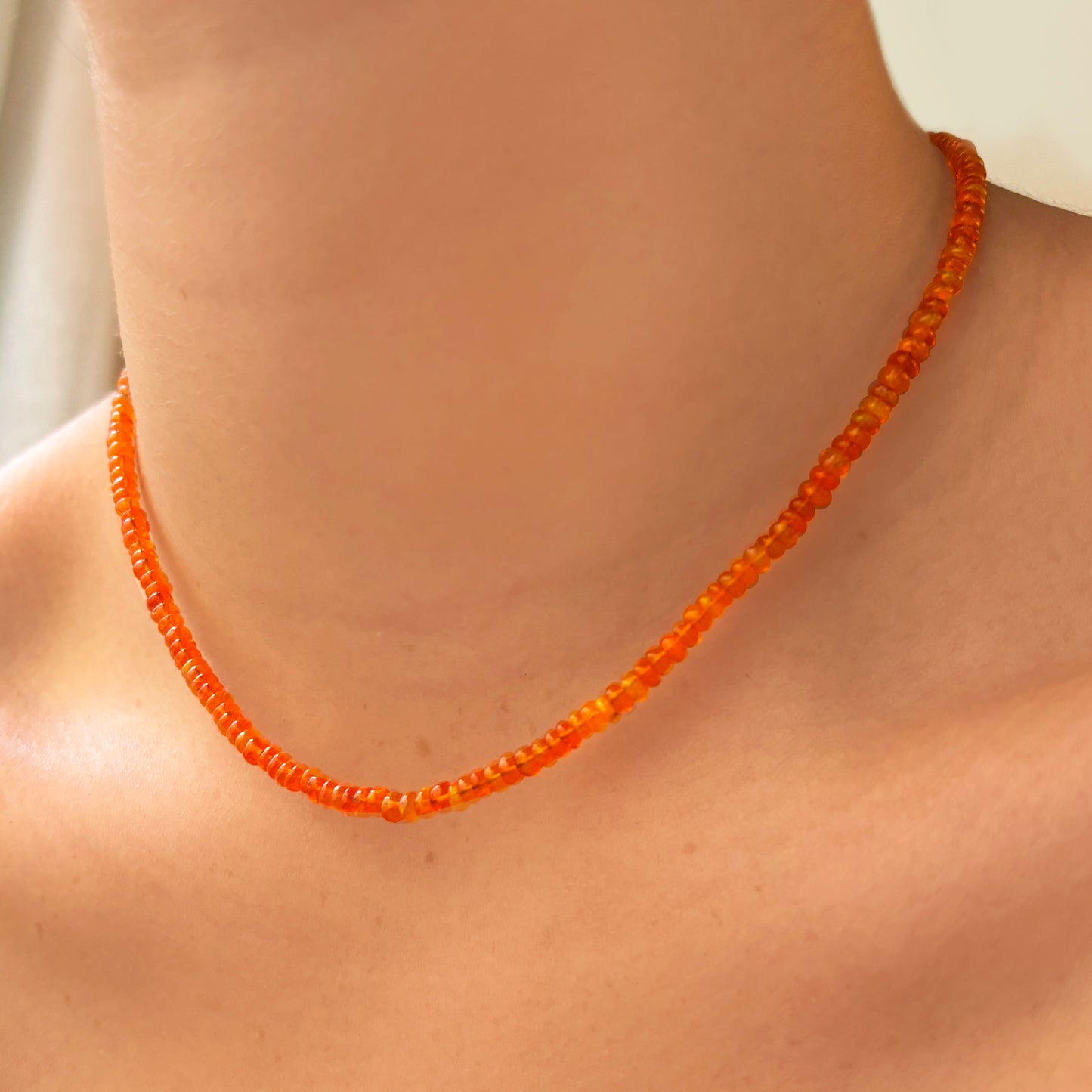 Shimmering beaded necklace made of smooth opal rondels in shades of orange on a slim gold lobster clasp. 