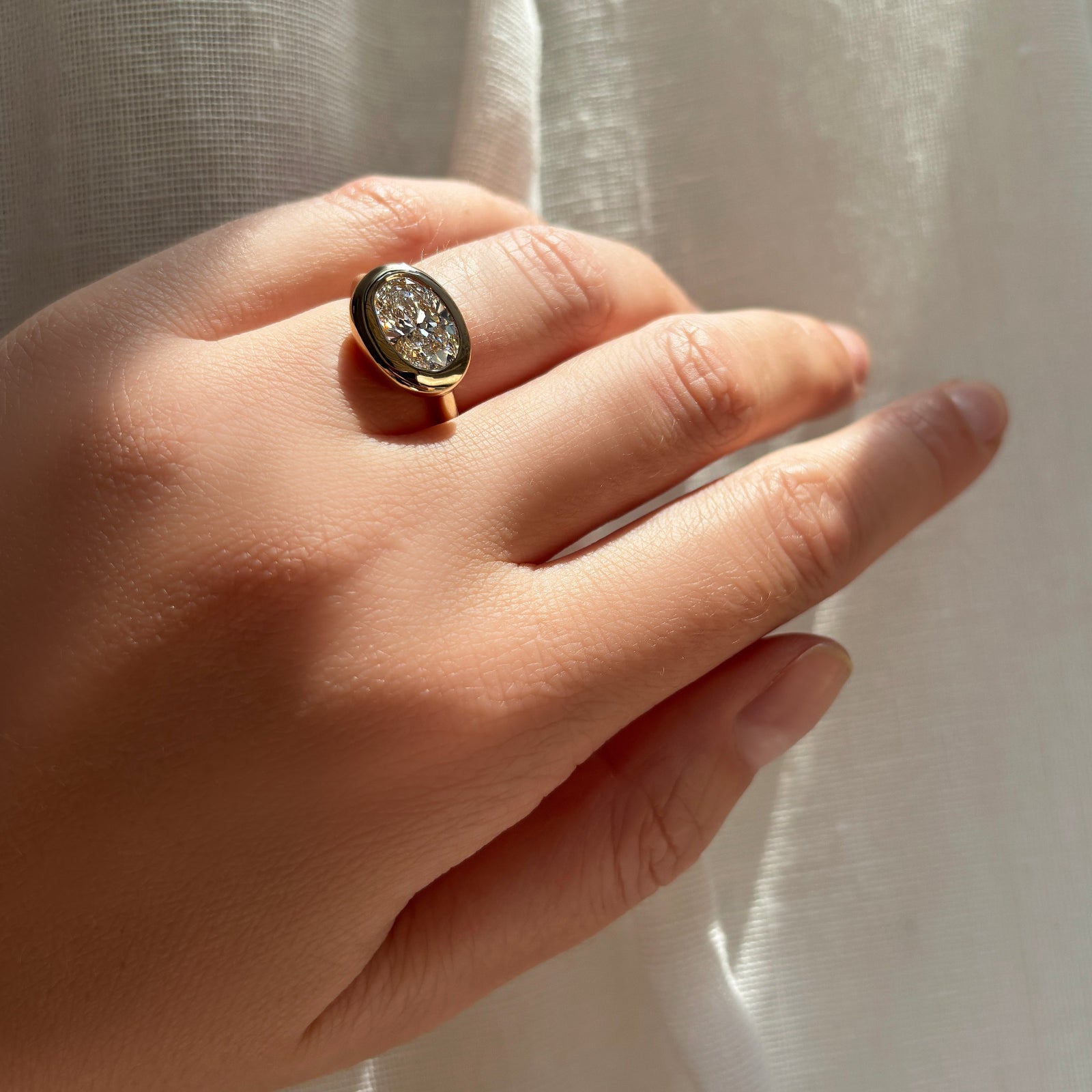 oval molten diamond solitaire ring on the hand with shadows.