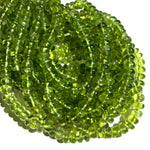A stack of AMANDA PEARL peridot rondelle necklaces on a white background.