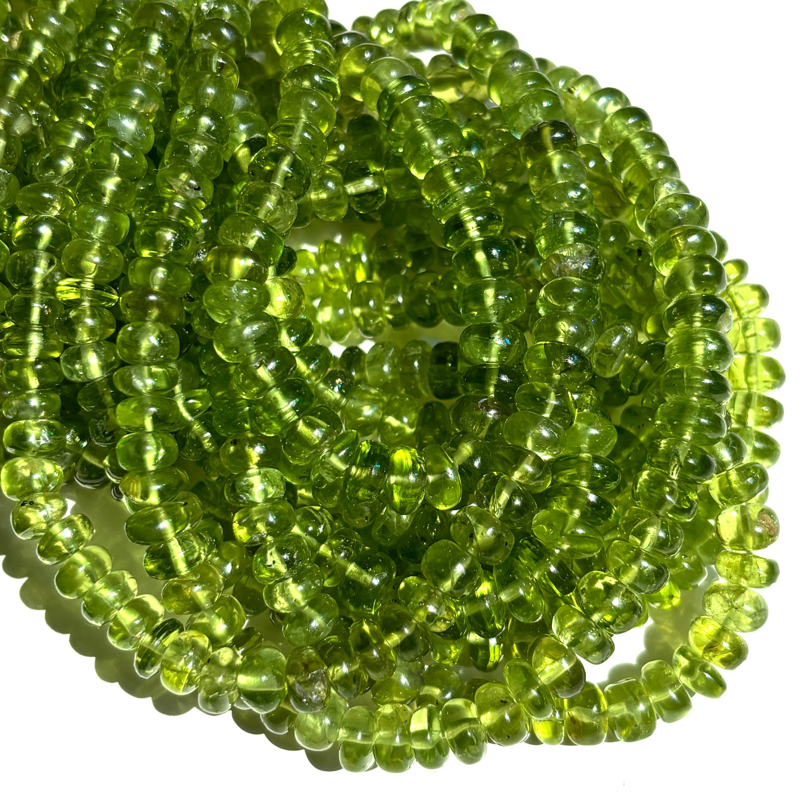 A stack of AMANDA PEARL peridot rondelle necklaces on a white background.