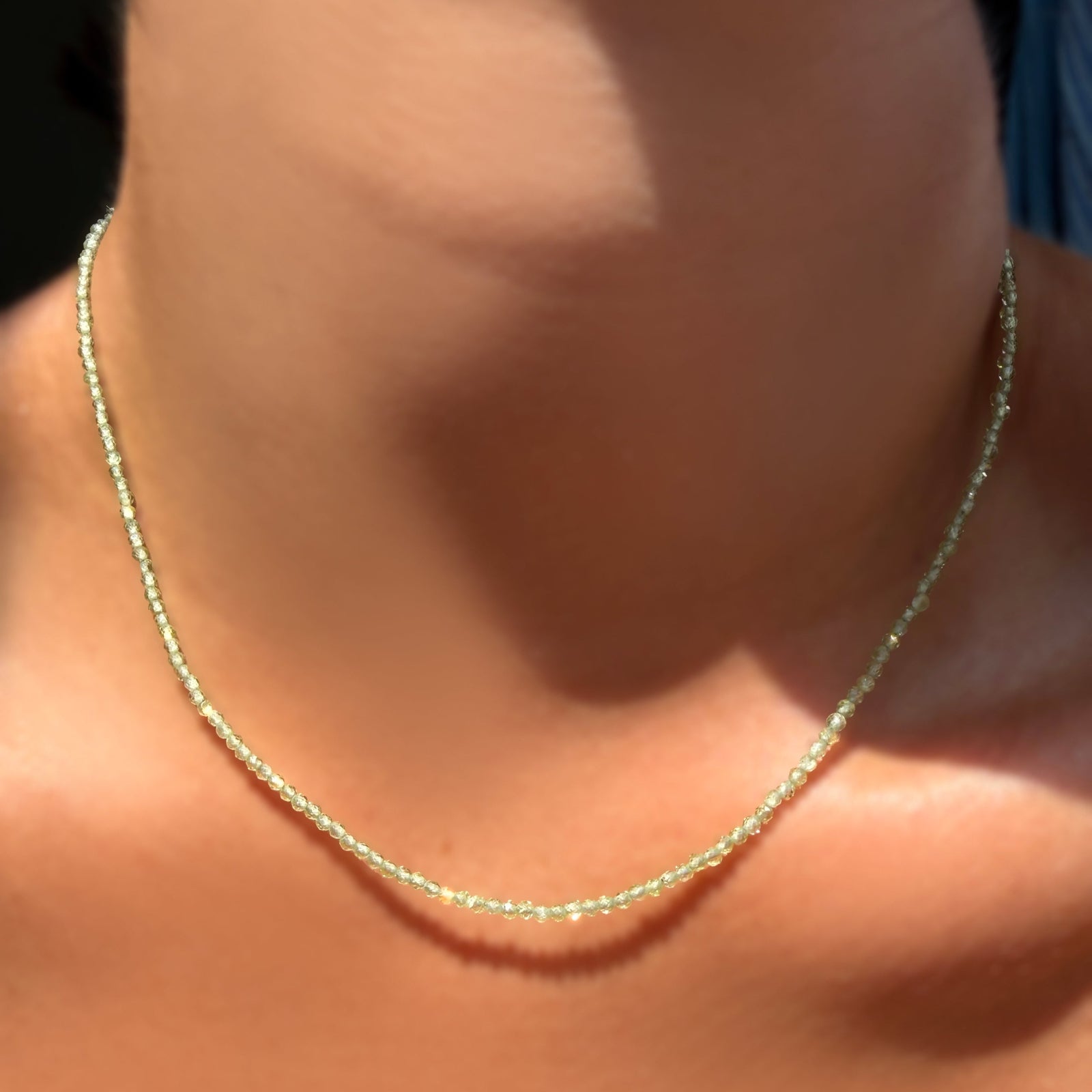 An AMANDA PEARL 2mm faceted peridot beaded necklace on a model's neck.