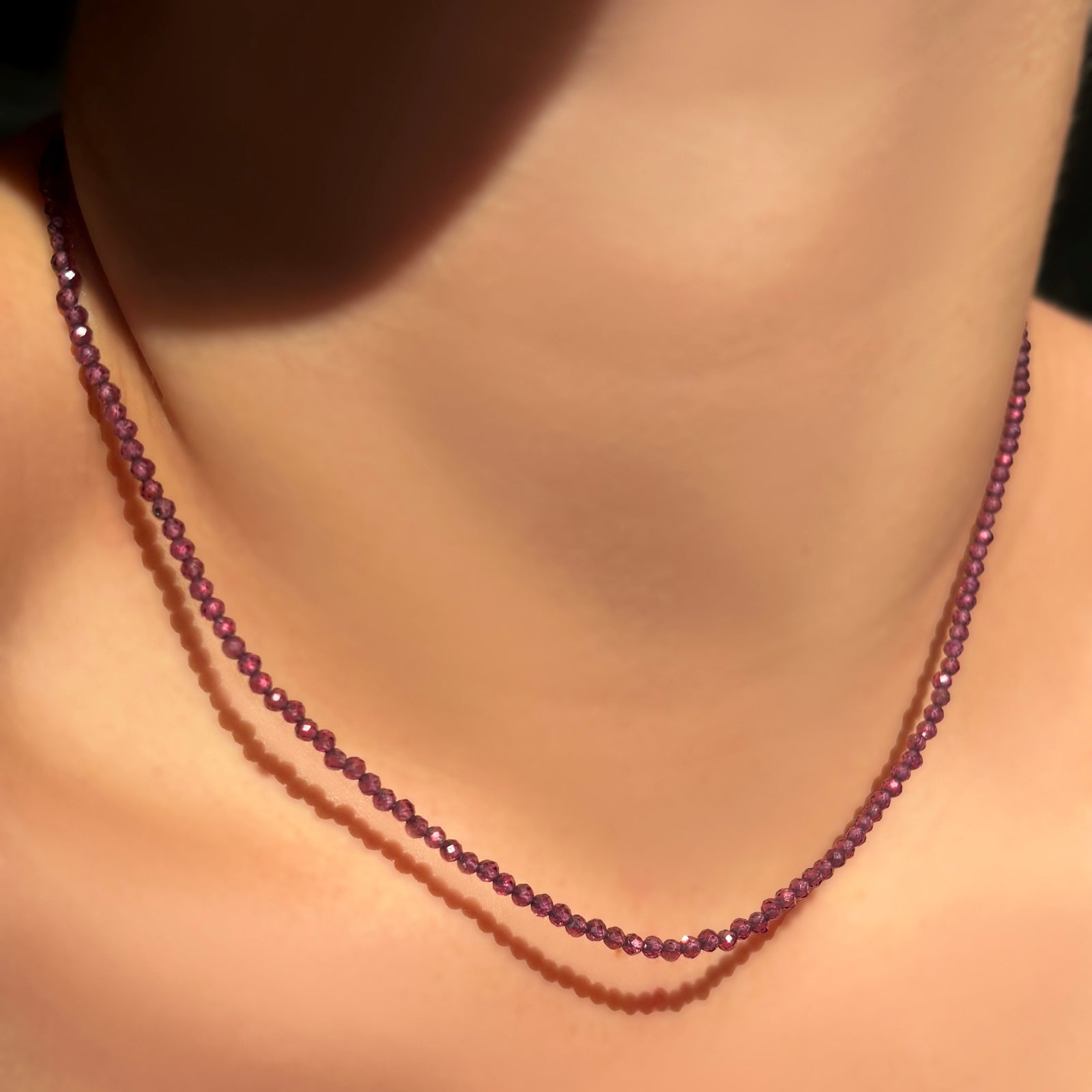 a single purple garnet slim faceted gemstone necklace on a model's neck.