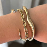 AMANDA PEARL recycled 14k gold and diamond quill cuff layered with drop link chain bracelet and molten cuff on a model's wrist.