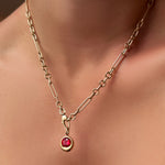 Round molten solitaire charm with ruby on a 6mm Irregular Cable Chain Necklace in 14k gold on a model's neck.