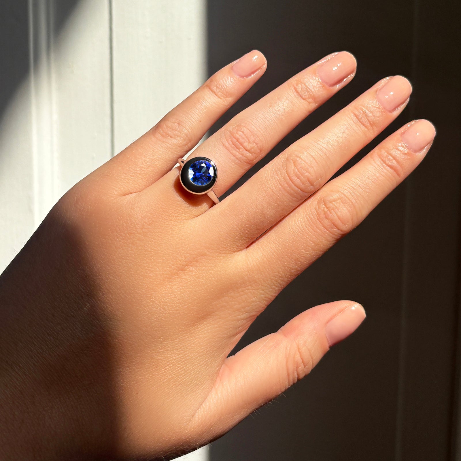 AMANDA PEARL Molten solitaire ring in recycled 14k gold with a cultivated sapphire center stone on a model's hand.