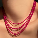 multiple faceted ruby slim gemstone necklaces on a model's neck.