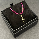 Ruby slim gemstone necklace with diamond cut bead chain with letter F charm bundled in a black jewelry box.