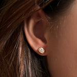 Single molten solitaire stud earring with an oval diamond in yellow gold on the ear. 