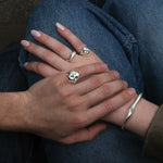 Close-up of two hands with AMANDA PEARL molten sterling silver rings over their denim clad legs.