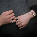 Two hands clasping pinkies wearing AMANDA PEARL sterling silver jewelry against a dark background.