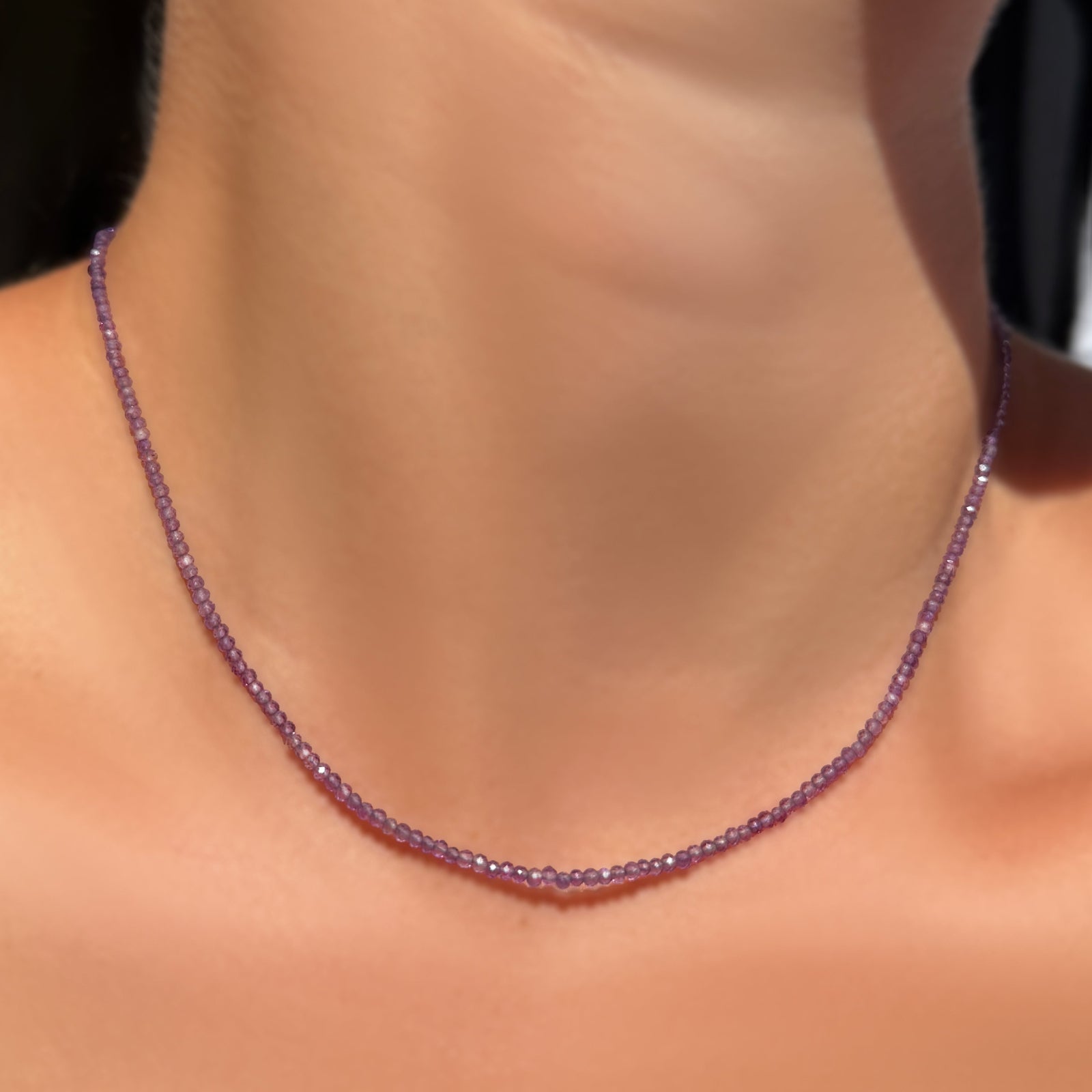 AMANDA PEARL Slim Gemstone Necklace with 2mm faceted amethyst beads on a recycled gold lobster clasp with extender chain on a model's neck.