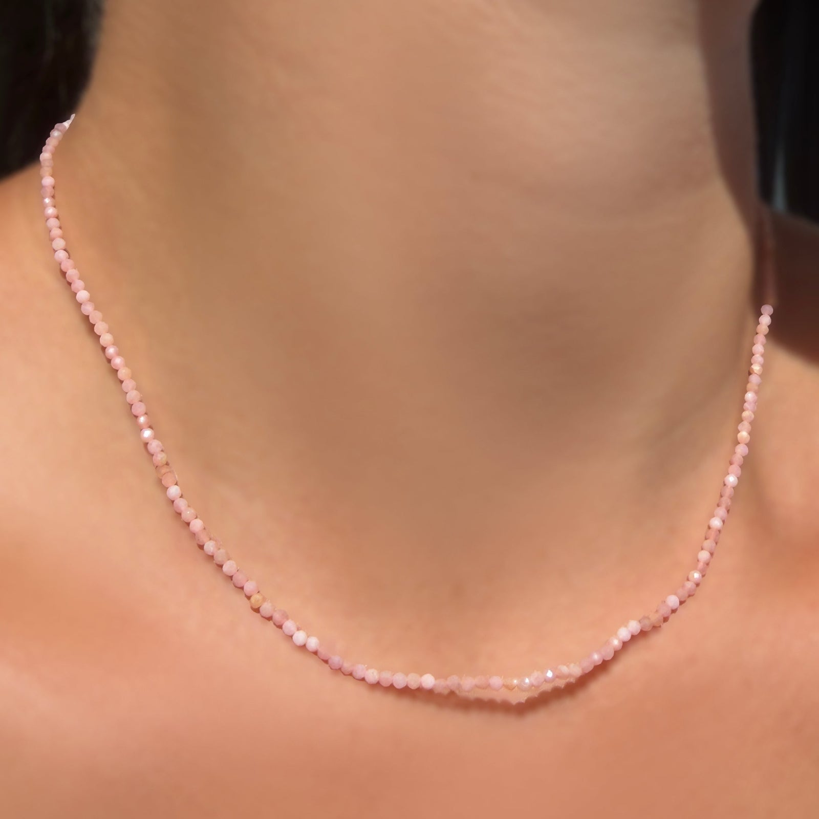 AMANDA PEARL Slim Gemstone Necklace with 2mm faceted pink opal beads on a recycled gold lobster clasp with extender chain on a model's neck.
