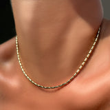 Sprinkle chain necklace in 14k yellow gold on a model's neck.