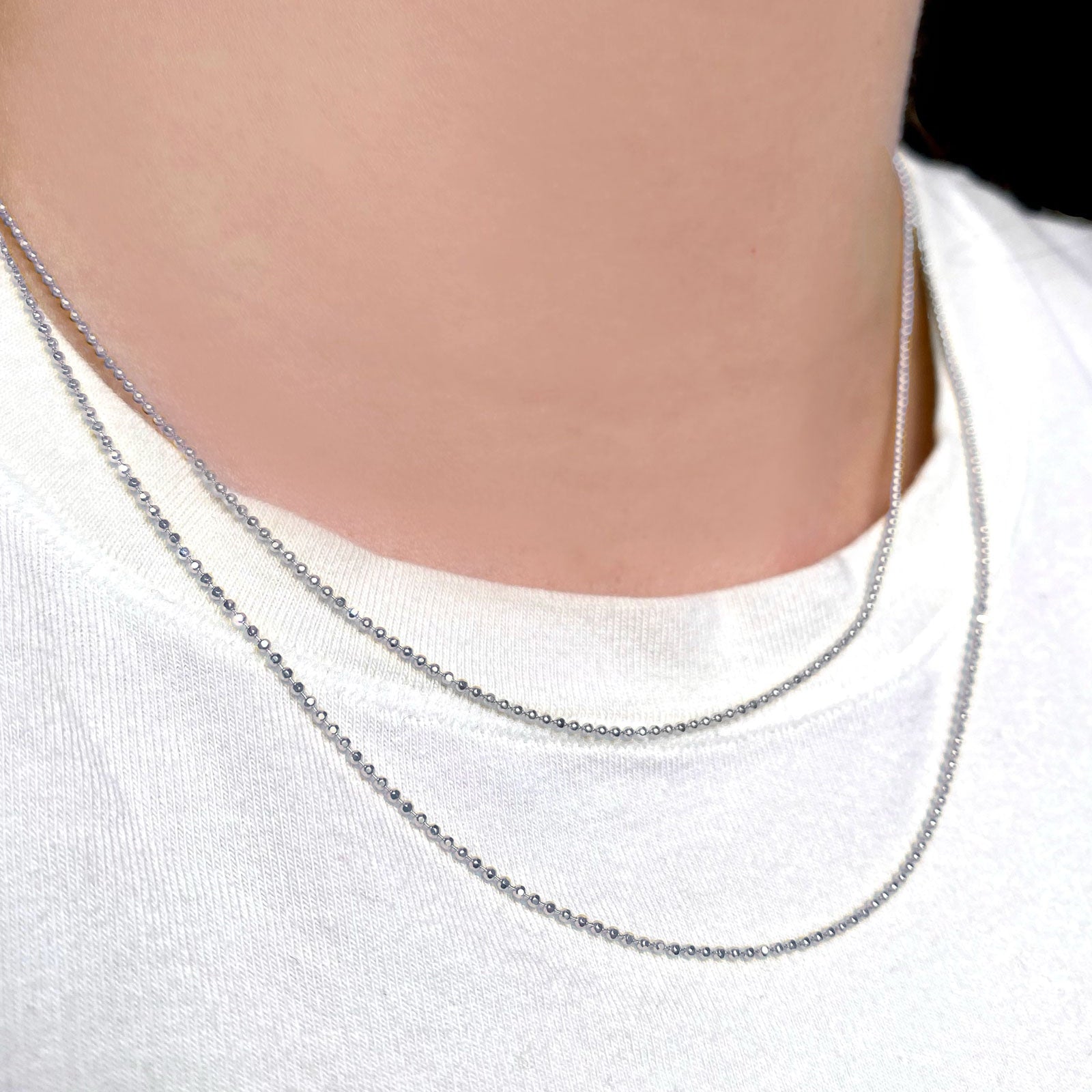 AMANDA PEARL sterling silver diamond cut bead chains on a model's neck over a white tee.