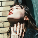 AMANDA PEARL Molten Skull Ring on a model's hand as she tilts her head toward the sun.