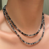 AMANDA PEARL faceted rutilated quartz necklaces with recycled sterling silver evolution clasps layered on a model's neck.