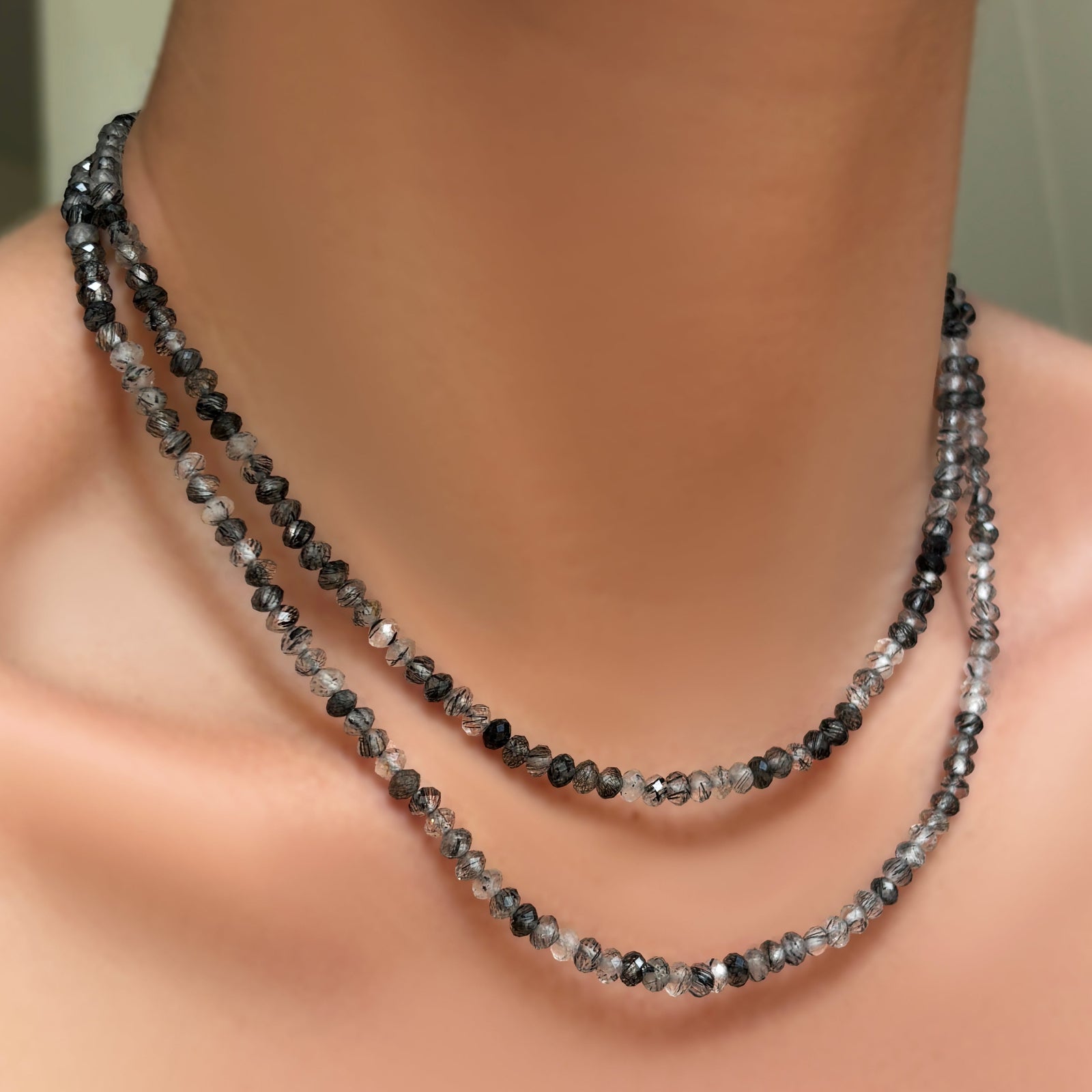 AMANDA PEARL faceted rutilated quartz necklaces with recycled sterling silver evolution clasps layered on a model's neck.