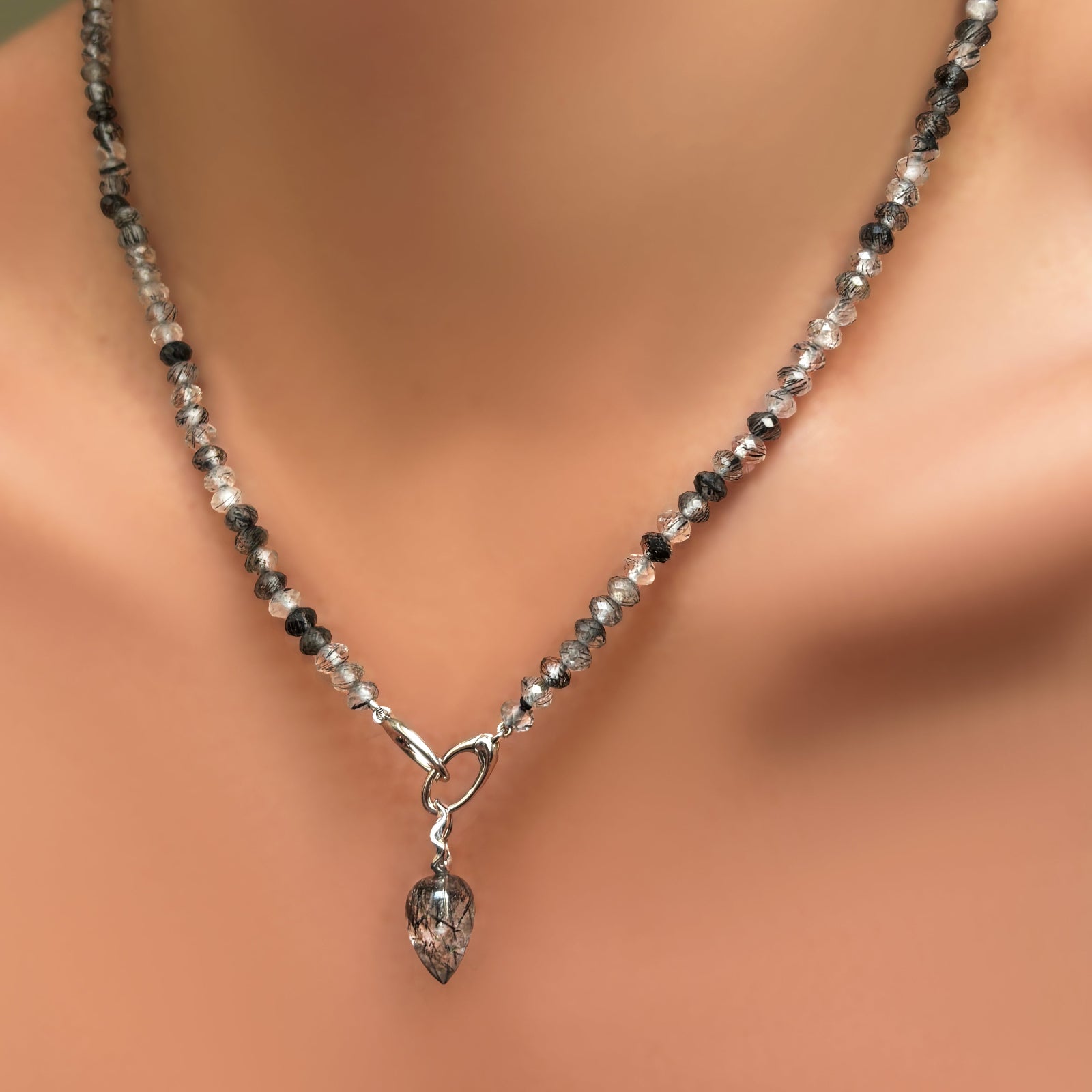AMANDA PEARL faceted rutilated quartz necklace with recycled sterling silver evolution clasp  holding a rutilated quartz drop charm with recycled sterling silver ripple bale on a model's neck.