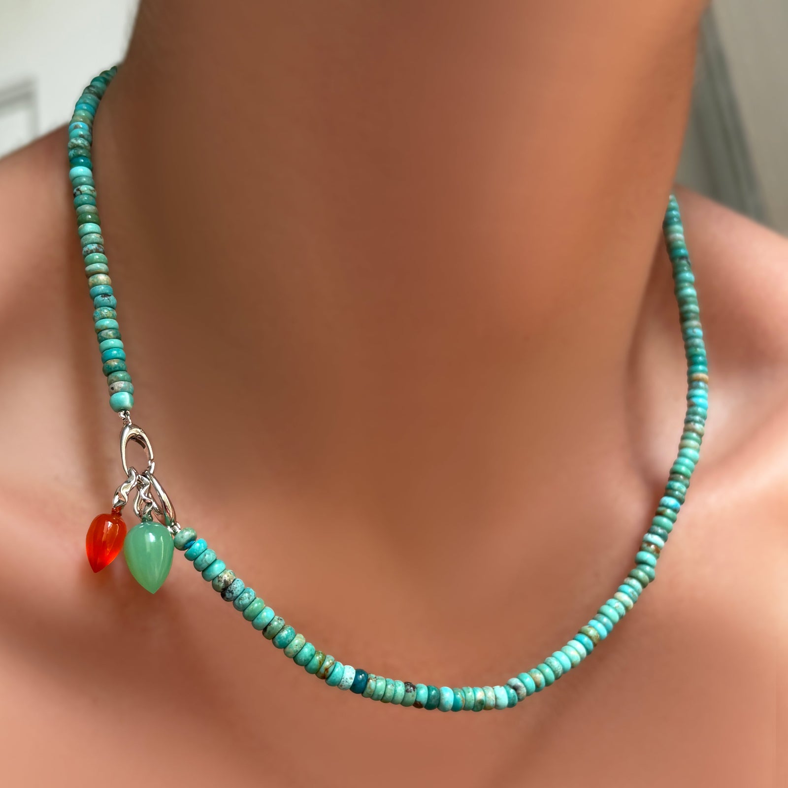 AMANDA PEARL turquoise rondelle necklace with sterling silver evolution clasp holding carnelian and chrysoprase drop charms on a model's neck.