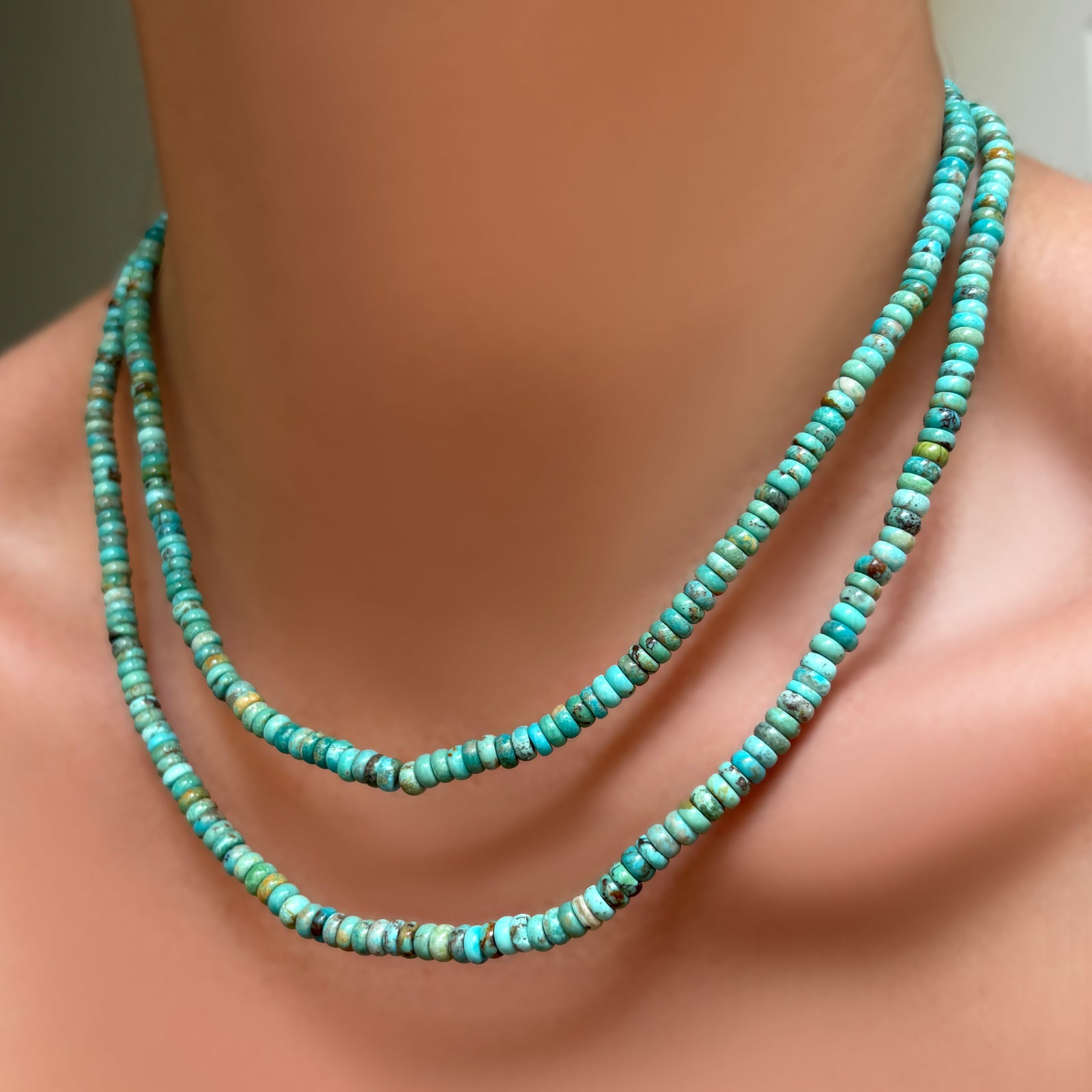 AMANDA PEARL turquoise rondelle necklaces with sterling silver evolution clasps layred on a model's neck.