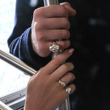 Two hands clad in AMANDA PEARL sterling silver molten rings holding the pole in a new york city subway car.