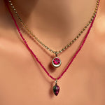 Necklace with a pendant featuring a red gemstone on a model.