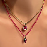 Necklace with a pendant featuring a red gemstone on a model.