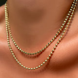 tibet chain layered with 3mm bead chain in yellow gold on a model's neck.