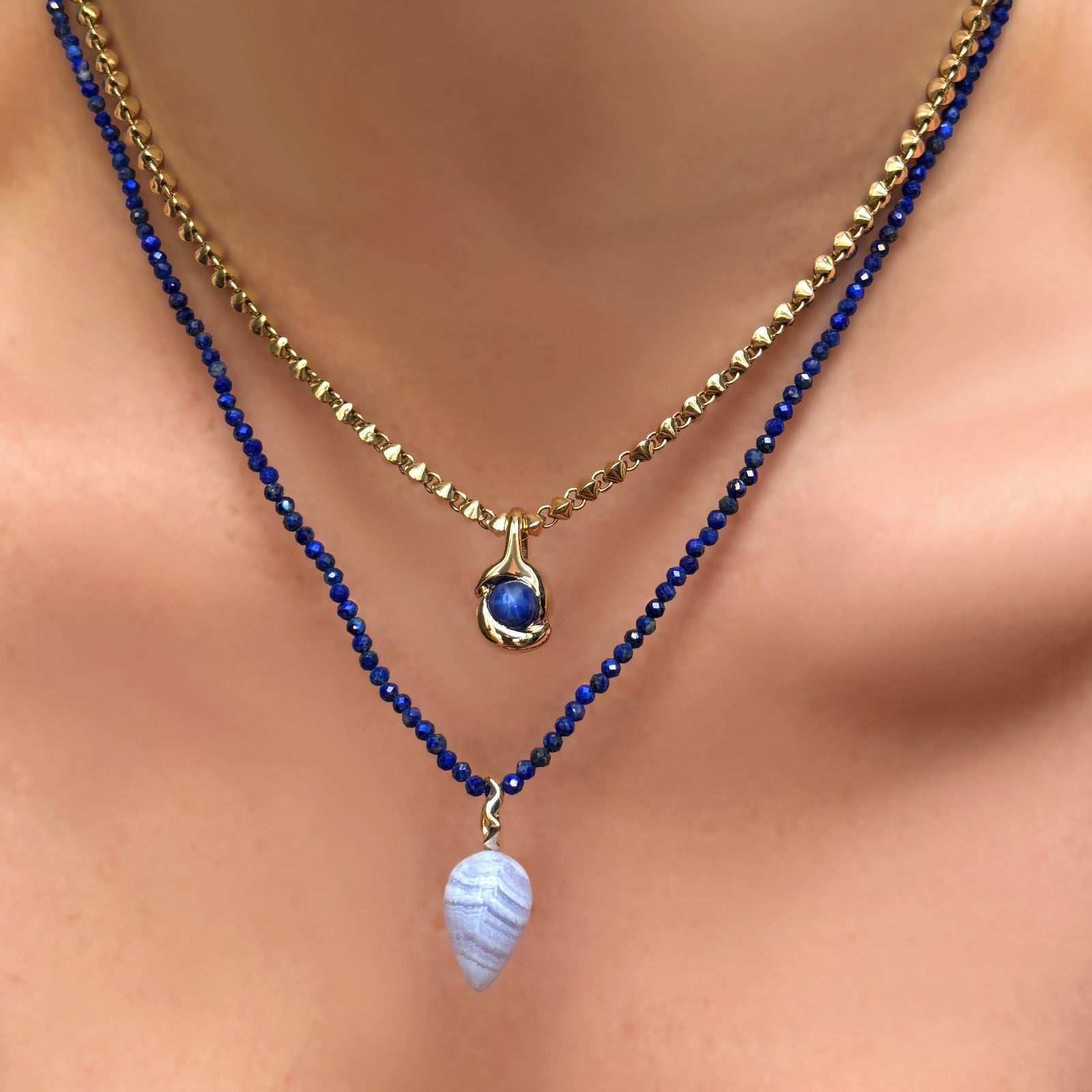 Lapis slim gemstone necklace with blue lace agate drop charm with ripple bale, layered on a model's neck with a 14k gold Tibet chain with molten knot charm with star sapphire.