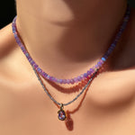 Necklace with an amethyst pendant on a neck against a dark background