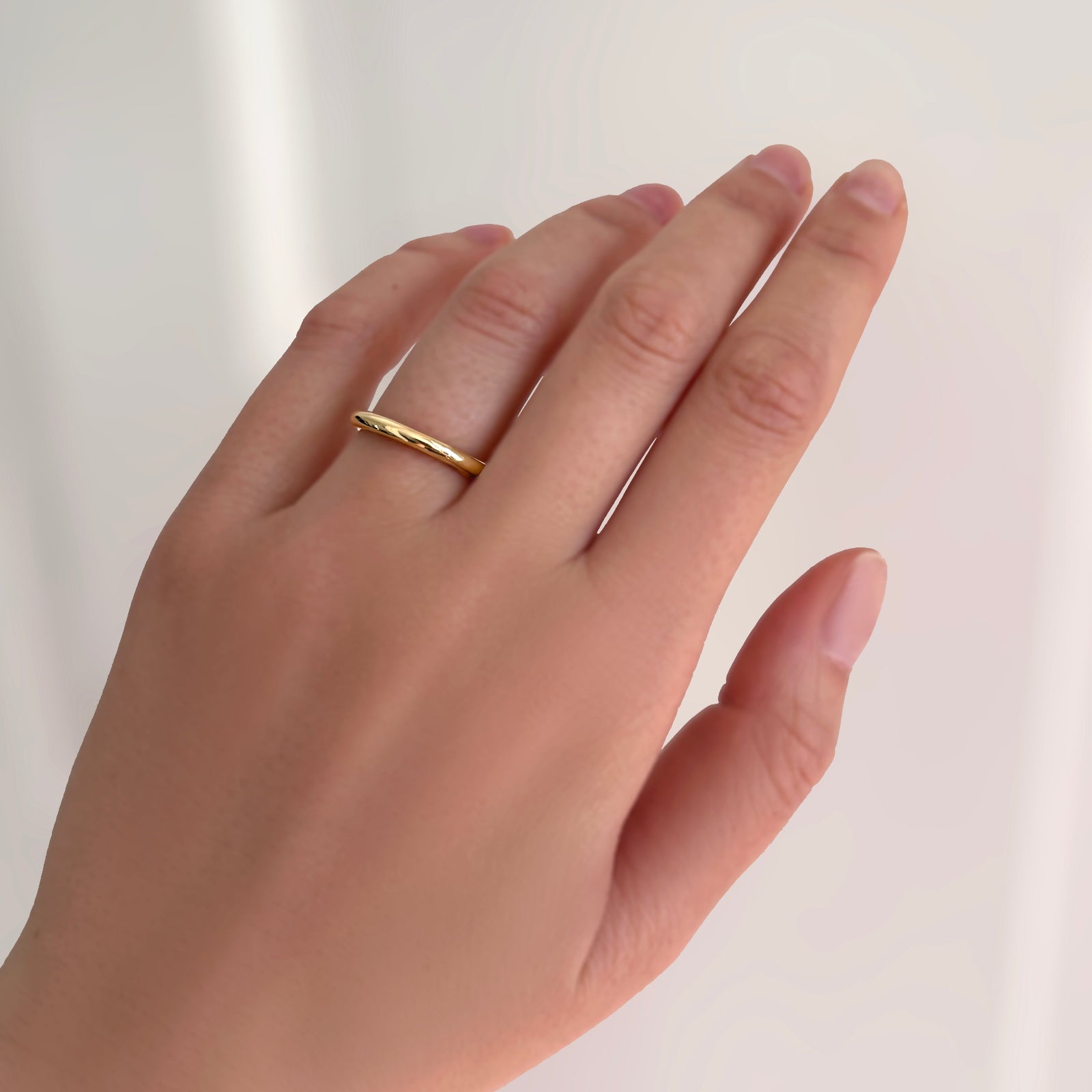 The AMANDA PEARL molten wedding band in 14K recycled yellow gold on a model's hand.