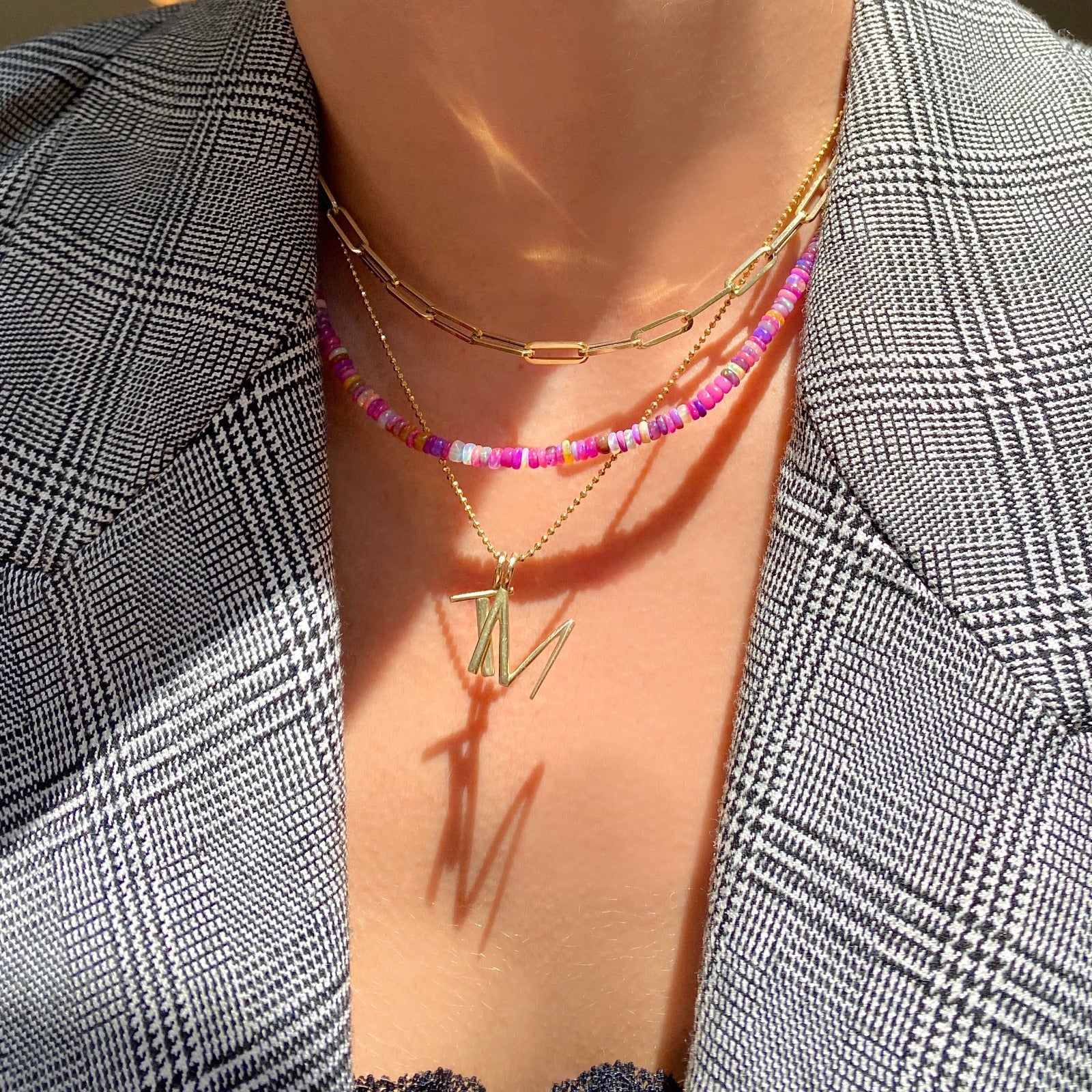 Shimmering Fuchsia Opal Necklace of smooth opals with various shades of pink, styled on a neck with a chunky paperclip chain and a diamond cut bead chain with letter charms T and M.