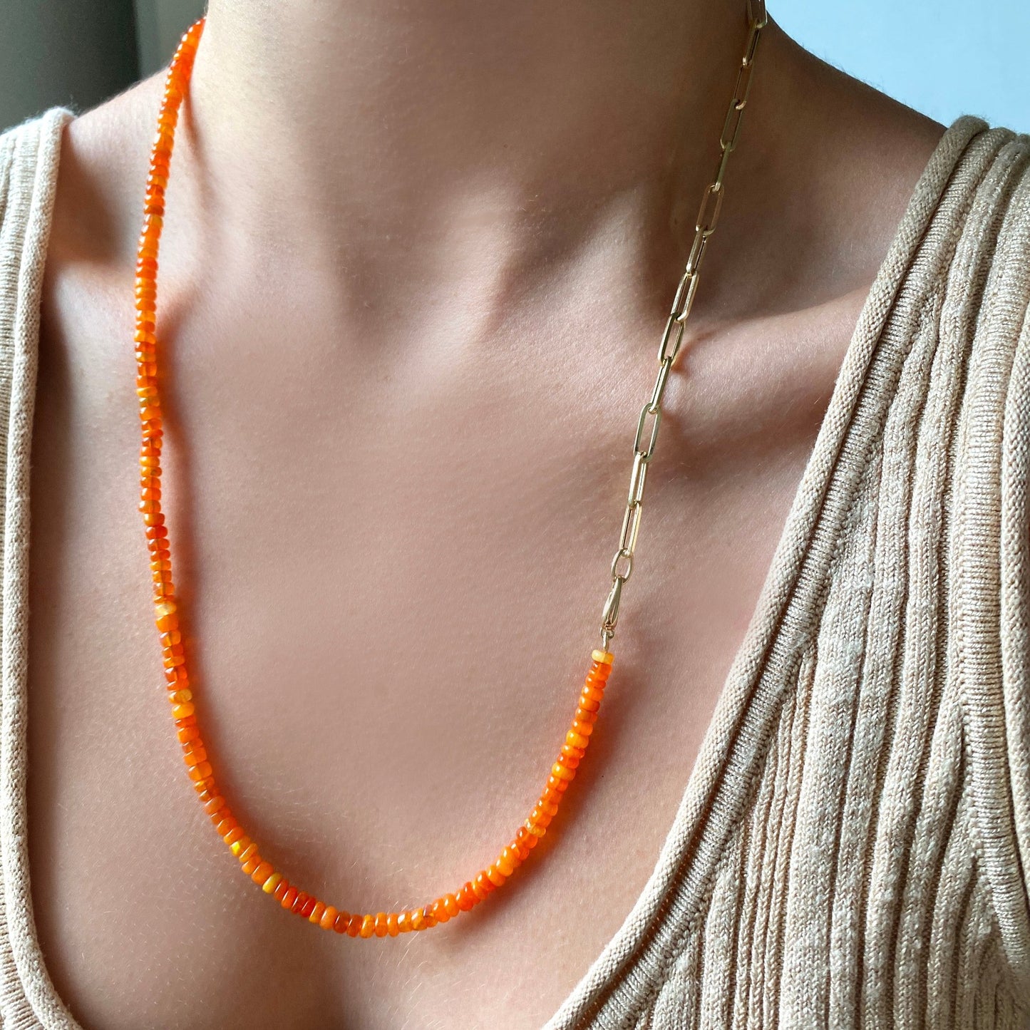 Shimmering beaded necklace made of smooth opal rondels in shades of orange on a slim gold lobster clasp. Styled on a neck layered with the paper clip chain necklace.
