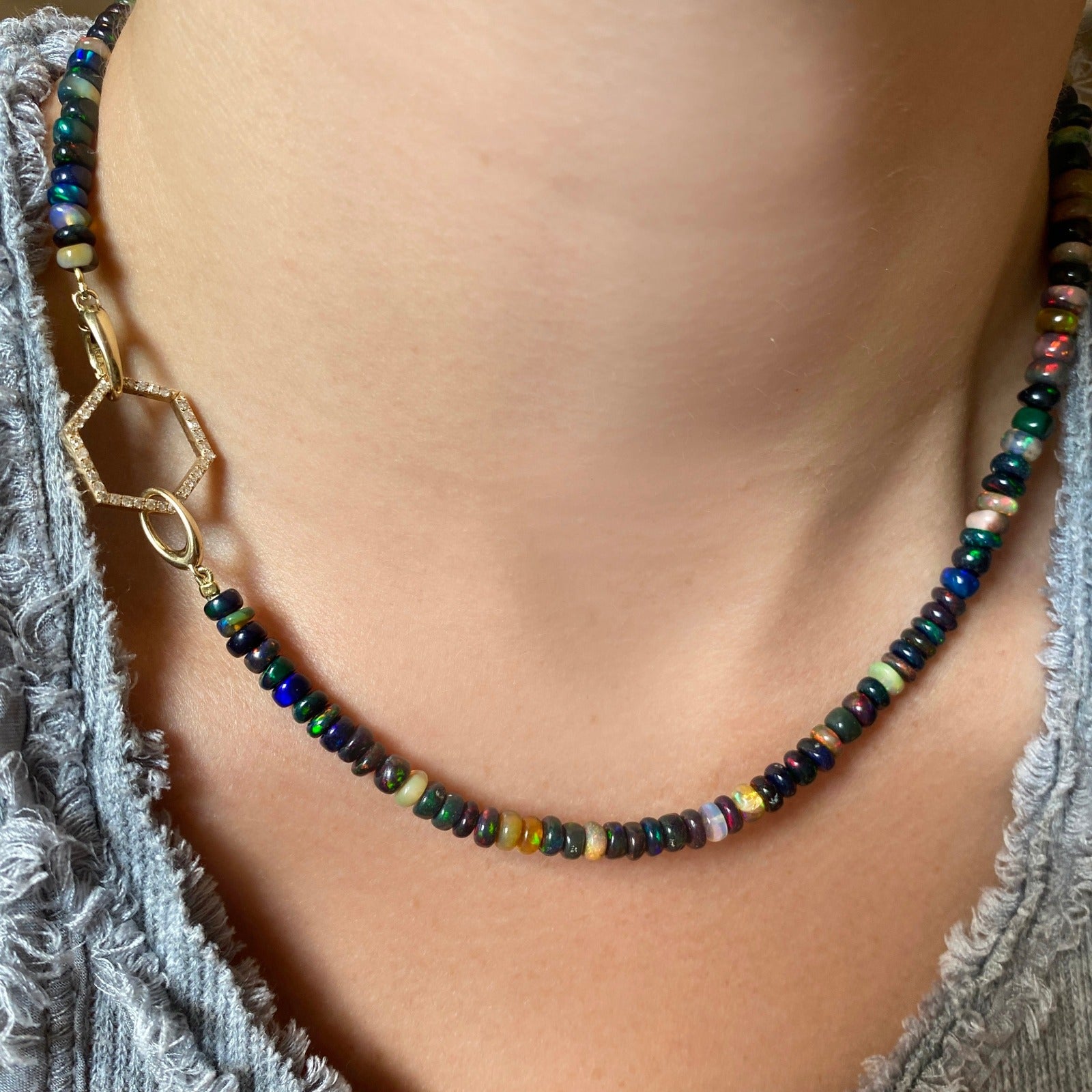 Shimmering beaded necklace made of smooth opal rondels in shades of black, dark green, navy, and clear on a slim gold lobster clasp. 