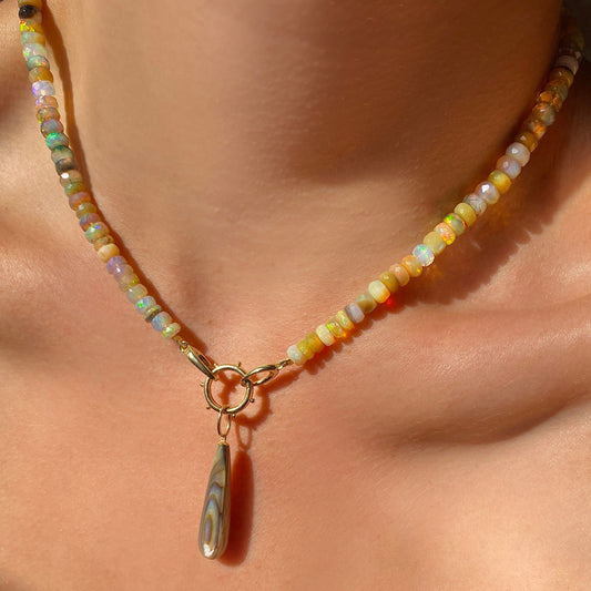 Paua Teardrop Charm with sahdes of brown, blue and gold styled on a gold beaded round charm lock linked to a faceted opal necklace.